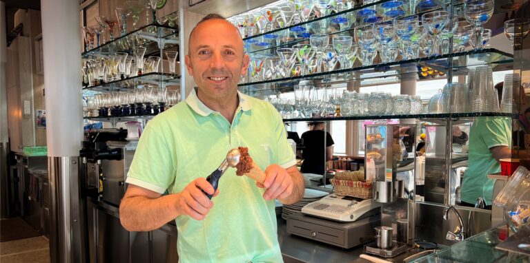 Fehmi Osmani, Inhaber des Eiscafés Michele in Dorsten, bereitet lächelnd eine Kugel Eis im Hörnchen zu.