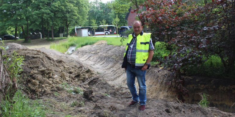 Ein Mann steht vor einem Graben in einer Grünanlage.