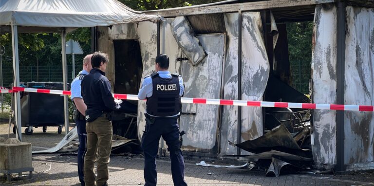 Polizisten und Kriminalpolizisten begutachten das ausgebrannte Corona-Testzentrum auf einem Parkplatz nahe des Schwimmbades Atlantis in Dorsten.