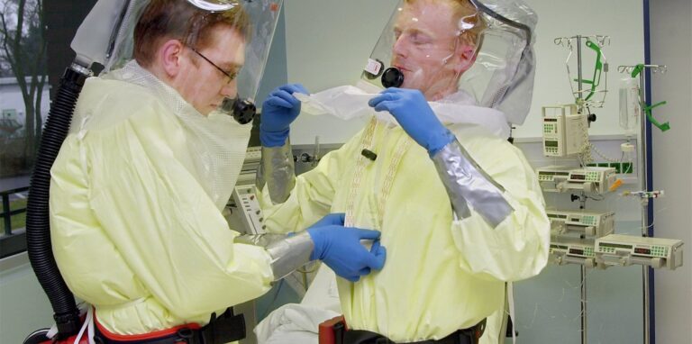 Zwei Pfleger helfen sich in der zentralen Isolierstation der Frankfurter Universitätsklinik am Montag (21.01.2002) gegenseitig in ihre Schutzanzüge.