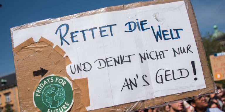 Schülerinnen und Schüler demonstrieren mit einem Protestplakat mit der Aufschrift «Rettet die Welt und denkt nicht nur ans Geld.»