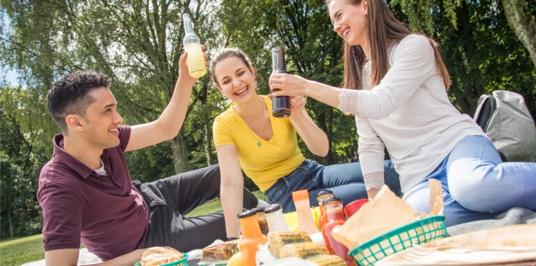 Drei junge Leute sitzen auf einer Picknick-Decke.