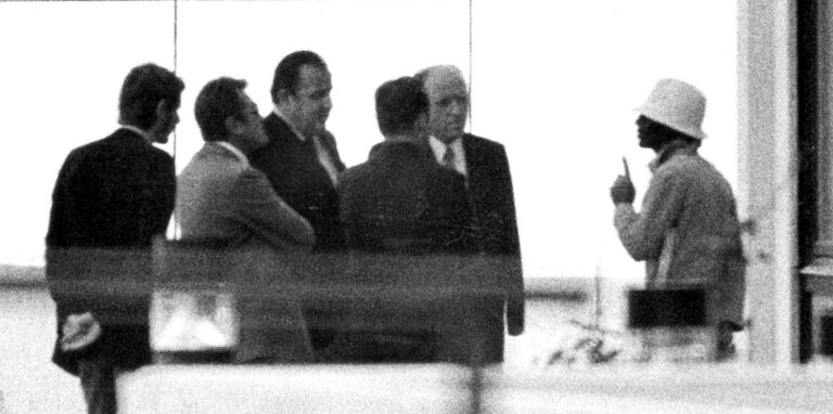 Archivbild: Ein Terrorist (r.) spricht am 05.09.1972 im israelischen Teamquartier im Olympischen Dorf der Münchner Sommerspiele mit Bundesinnenminister Hans-Dietrich Genscher (3.v.l.), dem bayerischen Innenminister Bruno Merck (2.v.r.), dem Münchner Polizeipräsidenten Manfred Schreiber (2.v.l.) und Dorf-Bürgermeister Tröger (3.v.l.).
