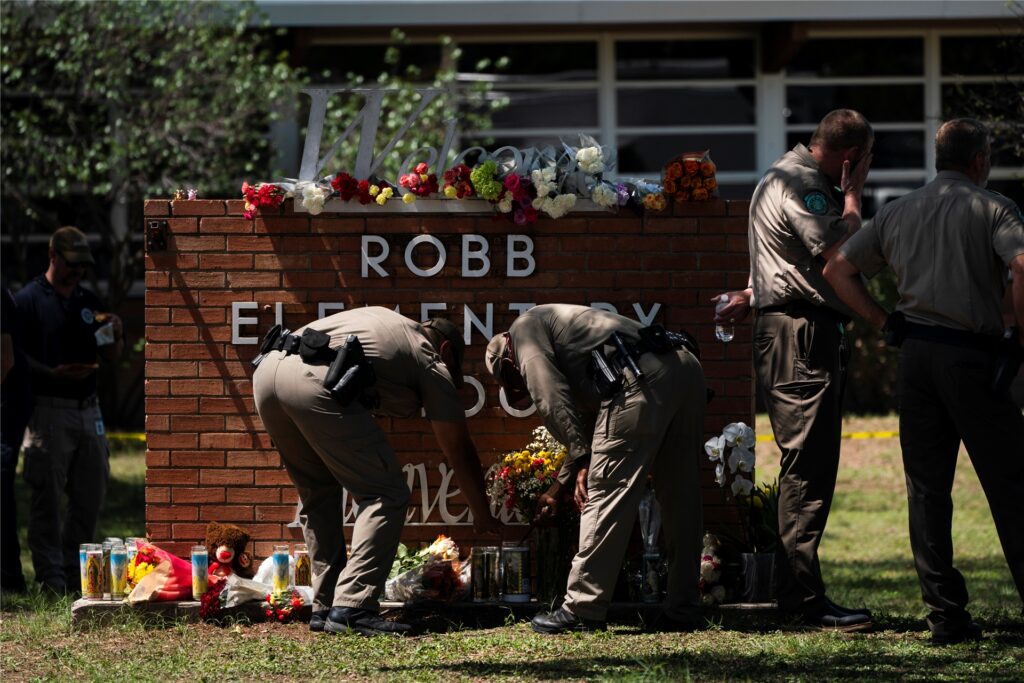 Zwei Polizisten zünden vor der Robb Elementary School eine Kerze an. Zwei Polizisten zünden vor der Robb Elementary School eine Kerze an.
