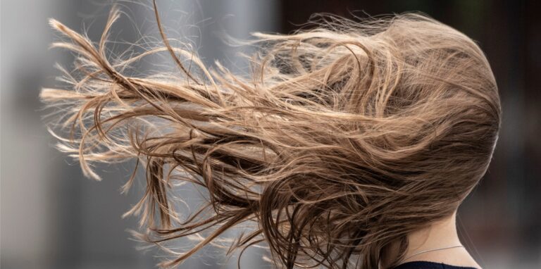 Ein stürmischer Wind lässt die Haare einer Frau wehen.