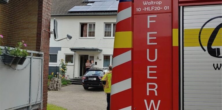Im Vordergrund ist ein Feuerwehr-Fahrzeug zu sehen, im Hintergrund ein Haus mit einer Photovoltaik-Anlage in Waltrop.