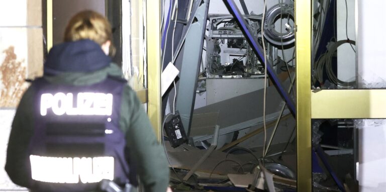 Eine Polizeibeamtin steht vor einem gesprengten Geldautomaten.