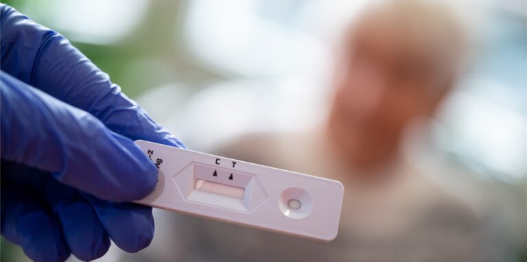 Eine Hand im Schutzhandschuh hält einen Antigen-Corona-Schnelltest.