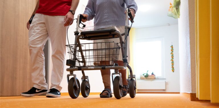 Pfleger und Senior mit Rollator
