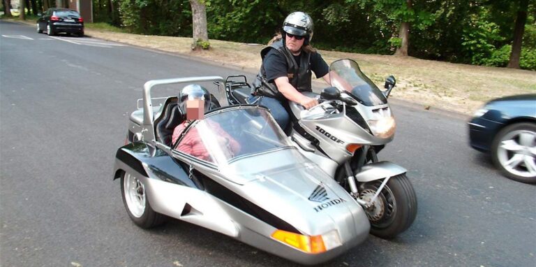 Ein Mann fährt in einem Honda-Motorrad mit Beiwagen durch die Straßen.
