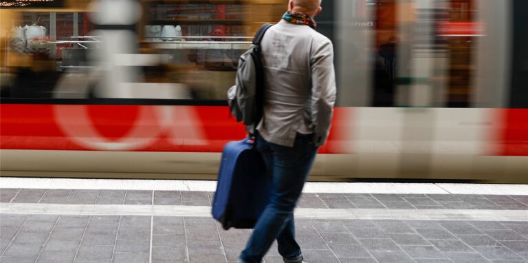 Ein Fahrgast geht zu einem einfahrenden Regionalzug am Bahnhof.
