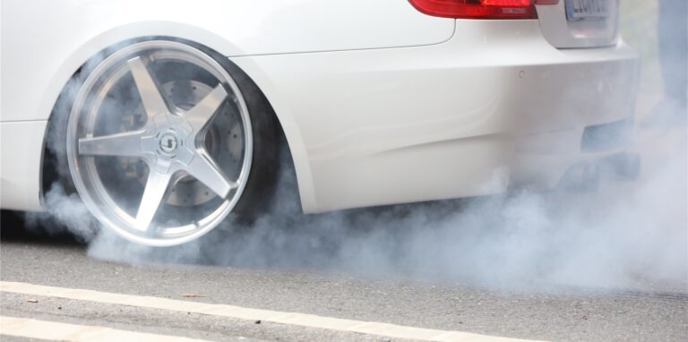 Beim Autotreffen drehen die Reifen des weißen Mercedes qualmend durch