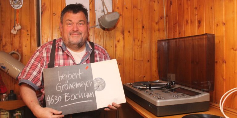 Detlef Pühs steht neben einem Plattenspieler und hält eine Herbert-Grönemeyer-Schallplatte in der Hand.