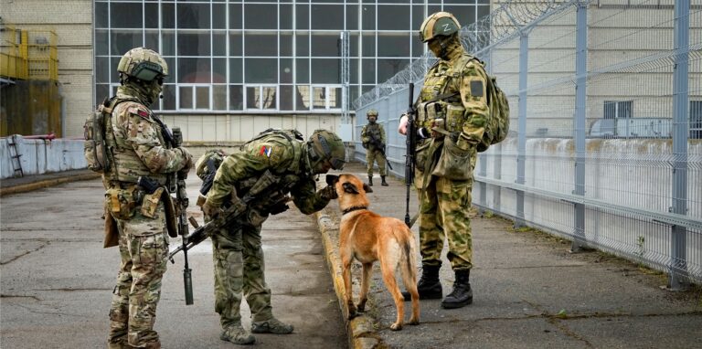 Russische Soldaten streicheln ihren Militärhund, während sie einen Eingang des Wasserkraftwerks Kachowka, eines Laufwasserkraftwerks am Dnjepr bewachen.