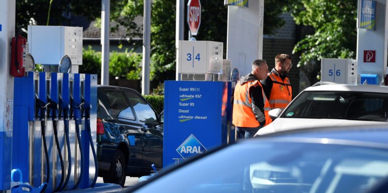 Zwei Männer tanken an den Zapfsäulen einer Tankstelle