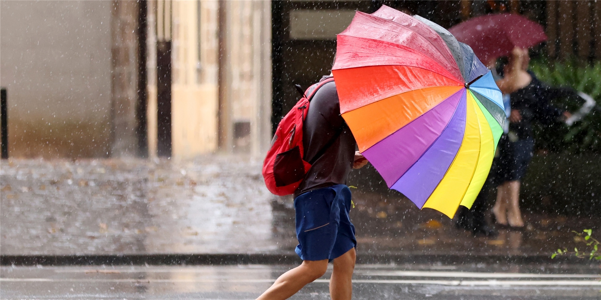 Eine Person mit einem Regenschirm geht im Zentrum von Sydney im Regen spazieren.