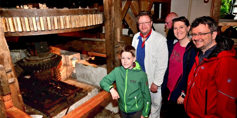 Gebannt schaut der 10-jährige Julian Monka auf die sich schnell drehenden Zahnräder und Wellen der Alt-Marler Wassermühle. Auch seine Eltern Stefanie und Jörg Monka hören den Erläuterungen von Mühlradfreund Stefan Jansen im weißen Müllerkittel zu.
