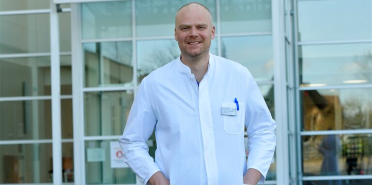 Dr. Lars Heining, Chefarzt der Lungenklinik Ruhrgebiet Nord, steht vor einem Gebäudeeingang.