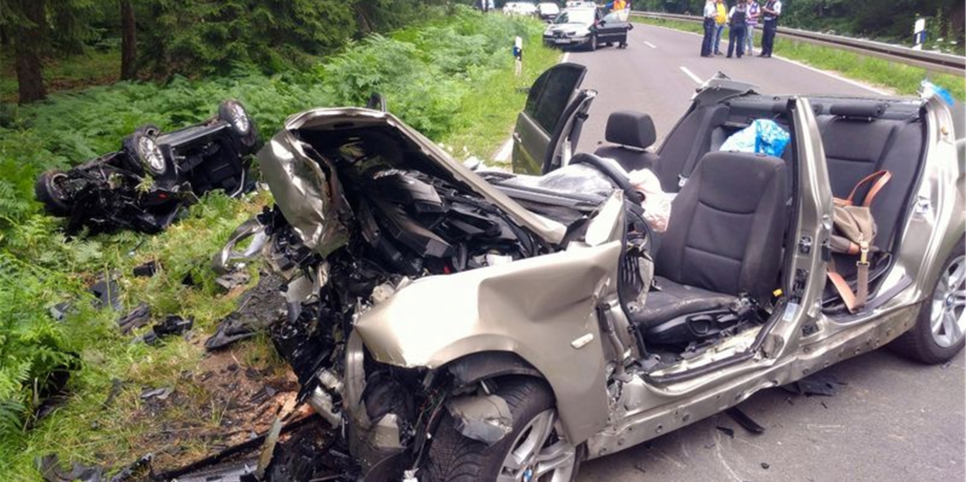 Zwei vollkommen zerstörte Autos liegen nach einem Unfall am Rand der Landstraße L12 zwischen Roetgen und Simmerath in der Eifel.