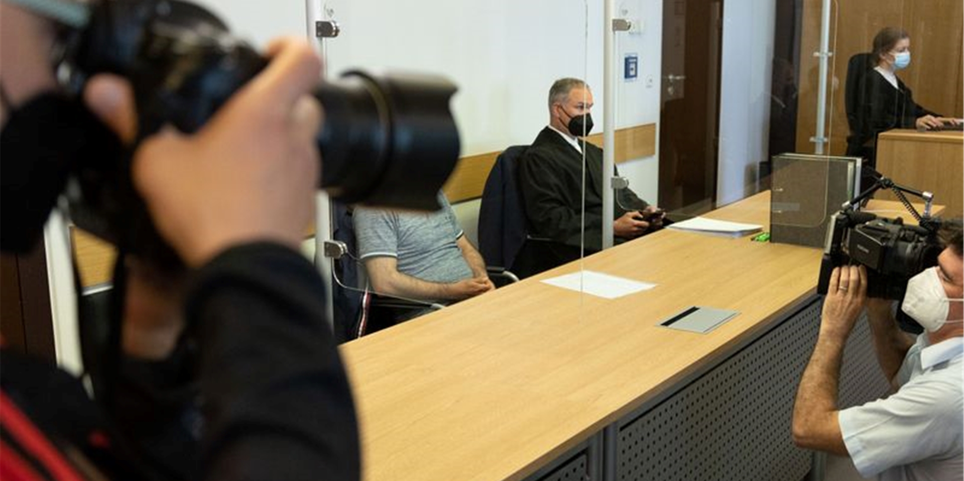 Der Angeklagte sitzt neben seinem Verteidiger (M) im Sitzungssaal im Landgericht.