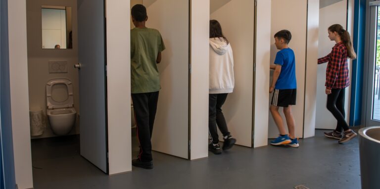 Jungen und Mädchen gehen in eine Unisextoilette.