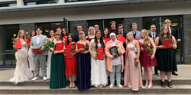 Elegant gekleidete Jugendliche stehen mit Abiturzeugnissen und Rosen auf einer Treppe in Recklinghausen.
