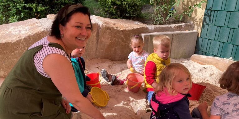 Eine Frau und Kinder im Sandkasten.