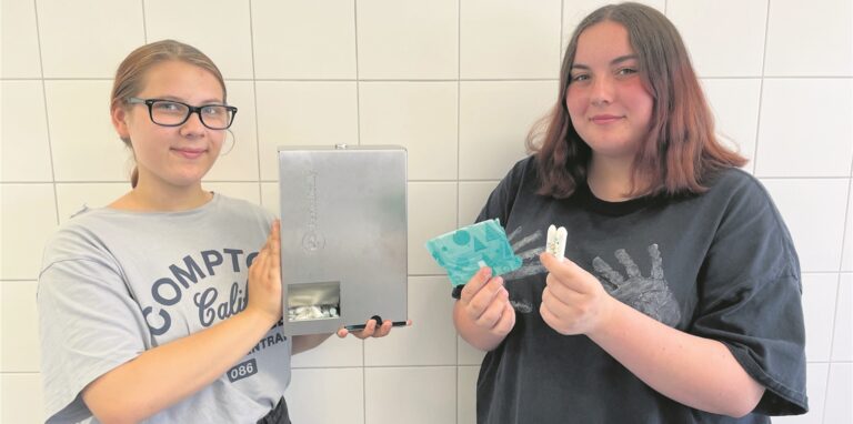 Julia Becker (15) hält den Spender für Hygienematerial in der Hand, der in der Mädchentoilette der Martin-Luther-Schule installiert wird. Monique Borkowski (15) zeigt, was drin ist: Binden und Tampons.