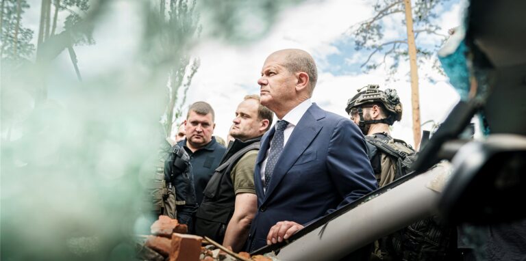 Bundeskanzler Olaf Scholz (SPD) steht an einem stark beschädigten Auto in Irpin im Großraum Kiew