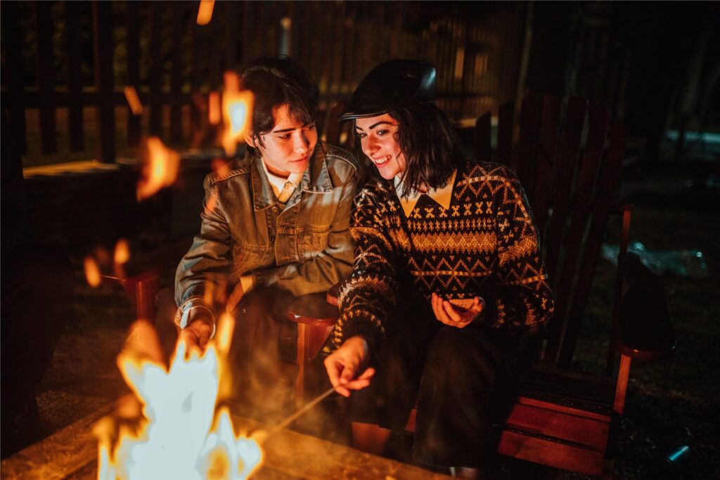 Zwei Frauen sitzen an einem Lagerfeuer und grillen Marshmallows