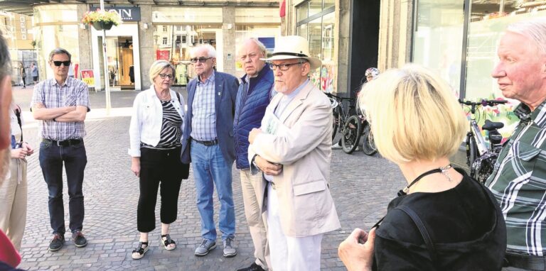 Eine Gruppe älterer Menschen steht auf einem Platz.