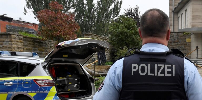 Ein Polizist steht neben einem Streifenwagen in Hagen.
