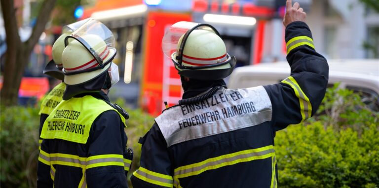 Feuerwehrleute vor einem geparkten Löschfahrzeug.