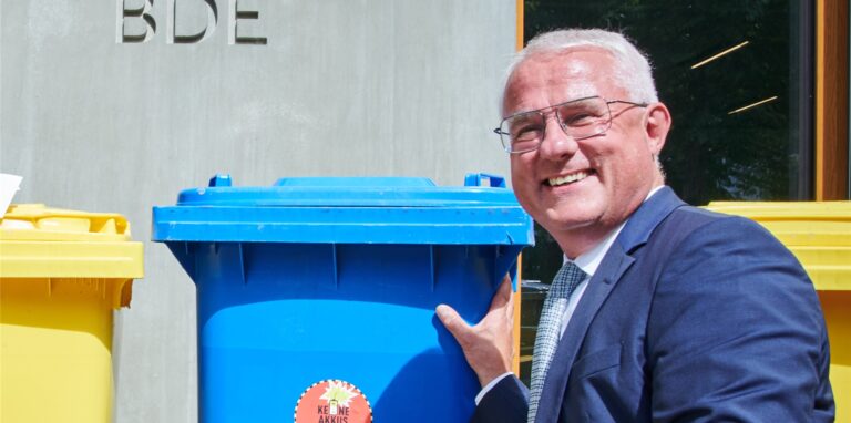 Peter Kurth, Präsident des Bundesverbandes der Deutschen Entsorgungs-, Wasser- und Rohstoffwirtschaft e.V. (BDE), steht vor Mülltonnen.