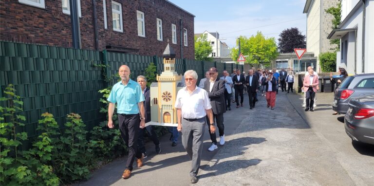 Eine Prozession trägt ein Modell einer Synagoge.