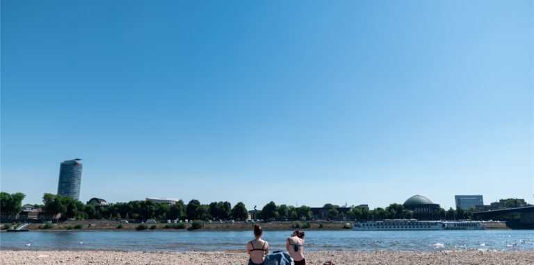 Zwei Frauen sonnen sich am Rheinufer.