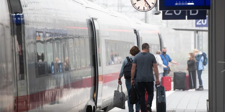 Bahnkunden gehen zu einem ICE.