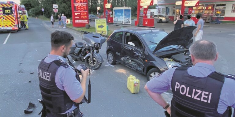 Zwei Polizisten nehmen einen Unfall mit Motorrad und Auto auf.