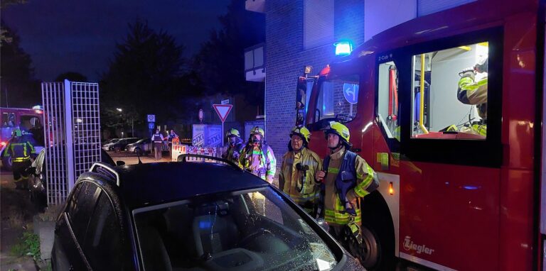 Einsatzkräfte der Feuerwehr stehen an einem Einsatzort.