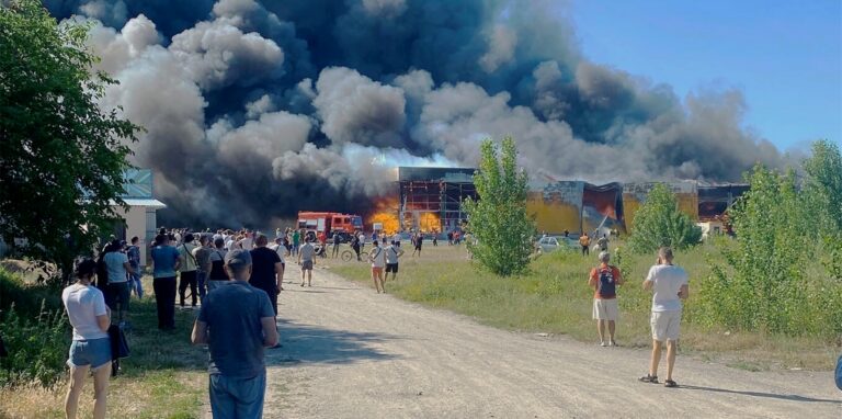 Nach dem Einschlag einer russischen Rakete in einem belebten Einkaufszentrum in Krementschuk, Ukraine, sehen Menschen Rauchschwaden.
