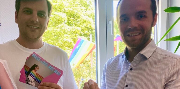Marc-Peter Selzer von den Grünen Waltrop und Bürgermeister Marcel Mittelbach halten Flyer für den Christopher Street Day in Waltrop in die Kamera.