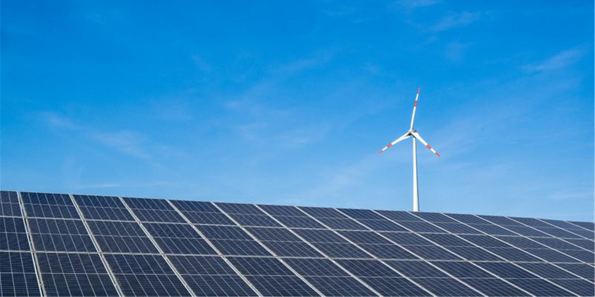 Ein Windrad hinter einem Solarfeld.