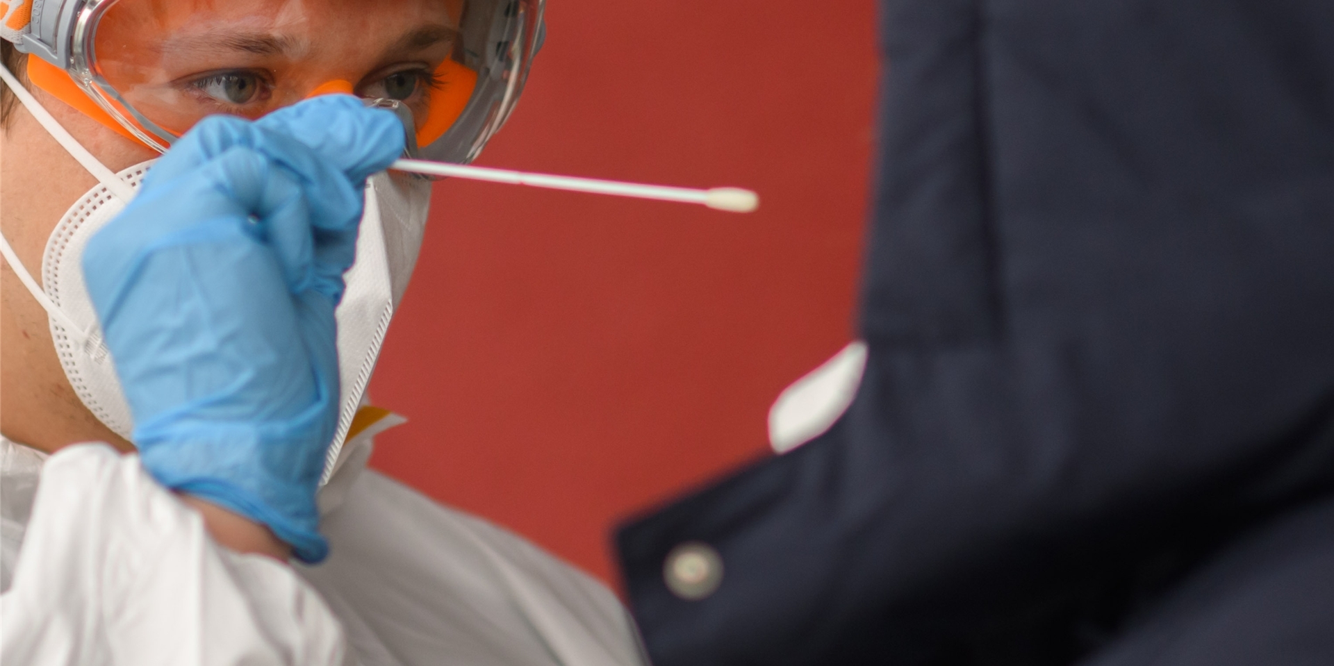 Ein Mitarbeiter nimmt einen Abstrich von einer Patientin für einen PCR-Test auf das Coronavirus.