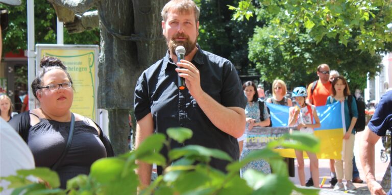 Björn Jadzinski aus Waltrop steht am Kiepenkerlbrunnen mit einem Mikrofon in der Hand.