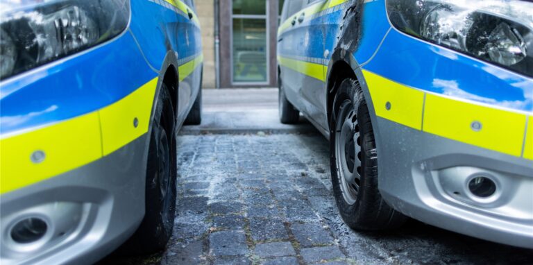 Zwei Polizeifahrzeuge mit Brandspuren stehen vor der Altstadtwache der Polizei.