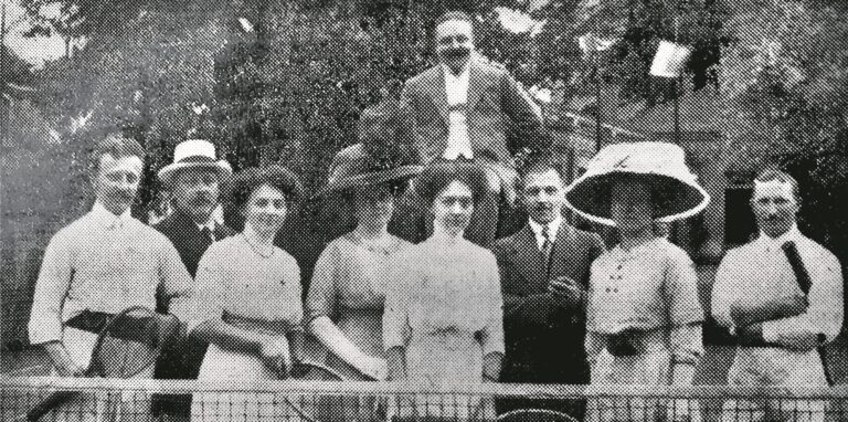 Ein Foto aus dem Jahre 1911 zeigt Männer und Frauen vor einem Tennisnetz mit Schlägern in den Händen.