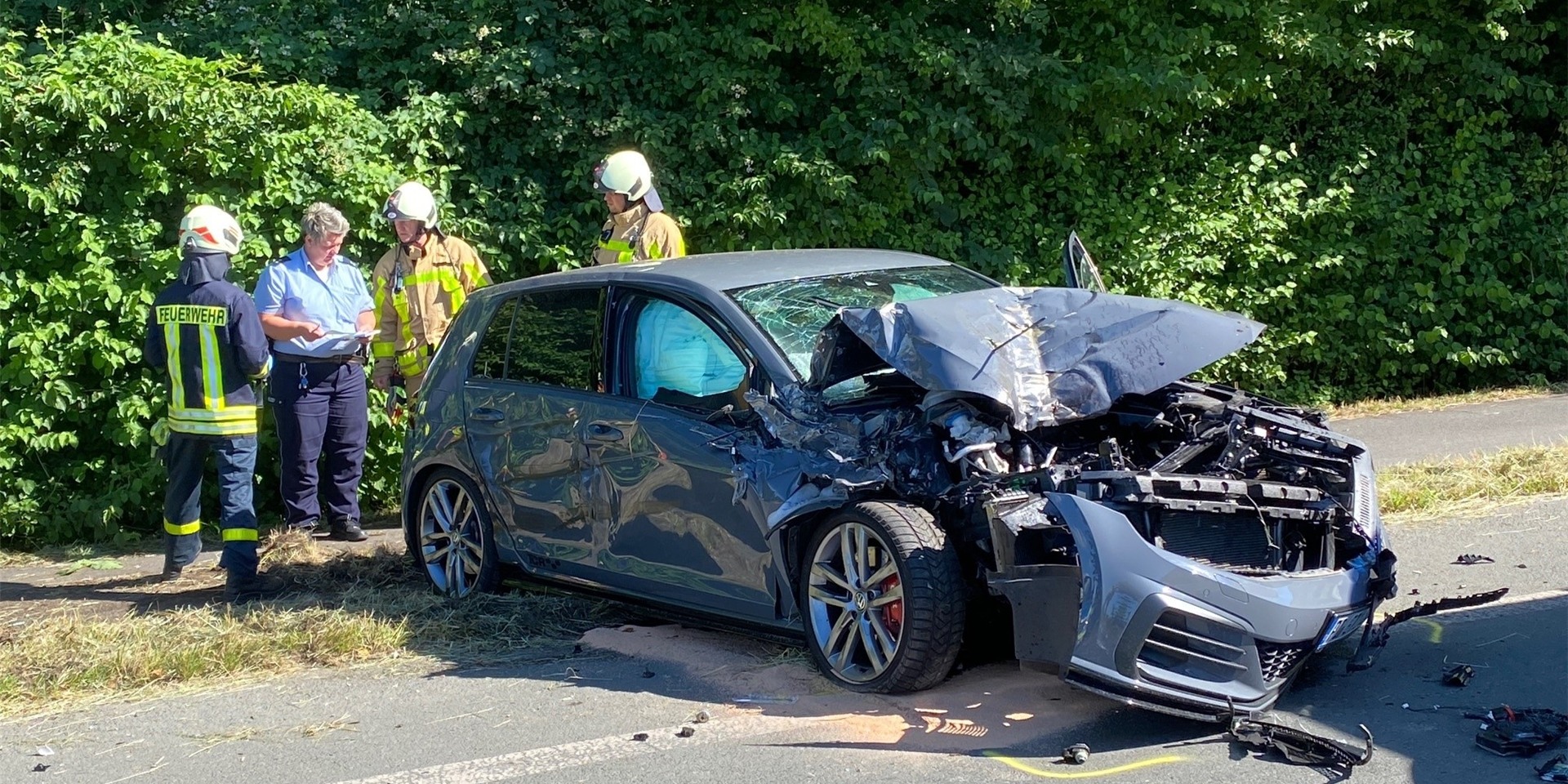 Ein völlig zerbeulter VW Golf an der Recklinghäuser Straße in Waltrop, im Hintergrund Einsatzkräfte von Polizei und Feuerwehr.