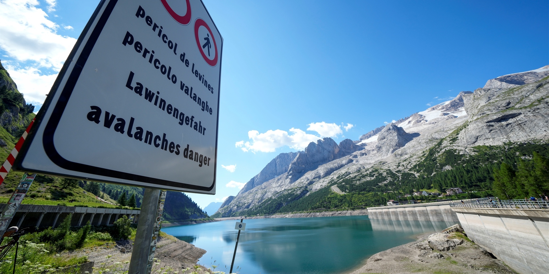 Ein Schild mit der Aufschrift „Lawinengefahr“ steht vor dem Marmolata-Berg und dem Punta-Rocca-Gletscher in den italienischen Alpen.