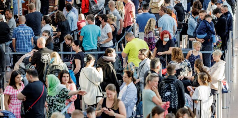 Fluggäste warten im Flughafen vor den Check-In Schaltern auf die Abfertigung.