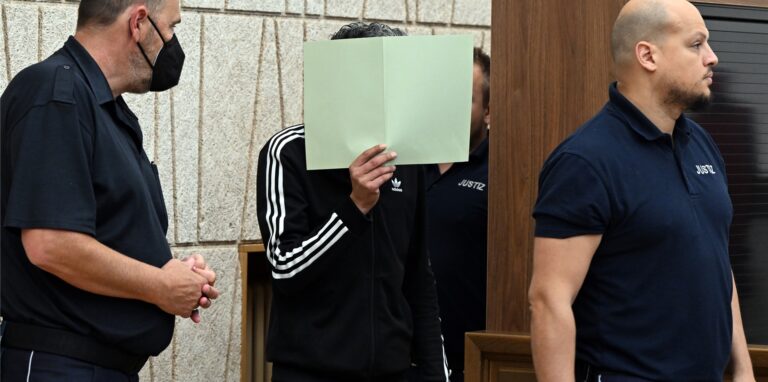 Der Angeklagte hält sich im Gerichtssaal eine grüne Mappe vor das Gesicht. Mehr als vier Jahre nach dem Säureanschlag auf einen Topmanager beginnt in Wuppertal der Prozess gegen einen der mutmaßlichen Attentäter.
